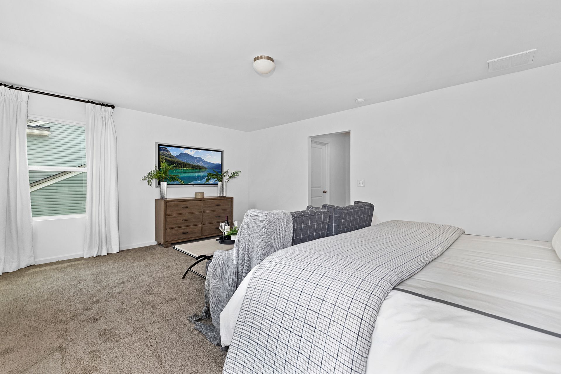 A bedroom with a bed , couch , television and window.