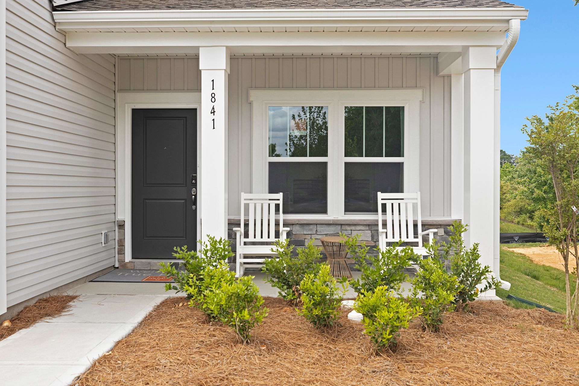 A white house with a porch and two white rocking chairs.