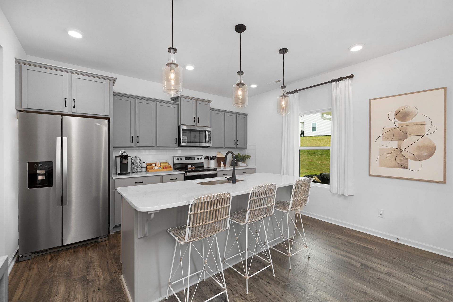 A kitchen with stainless steel appliances , gray cabinets , and a large island.