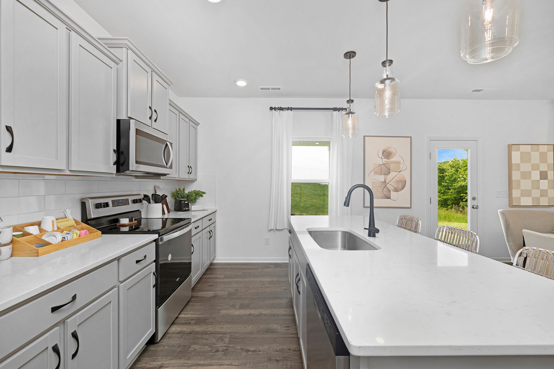 A kitchen with white cabinets , stainless steel appliances , and a large island.