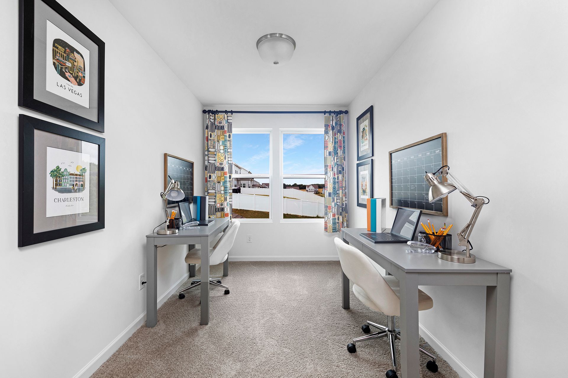 A home office with two desks and a large window.