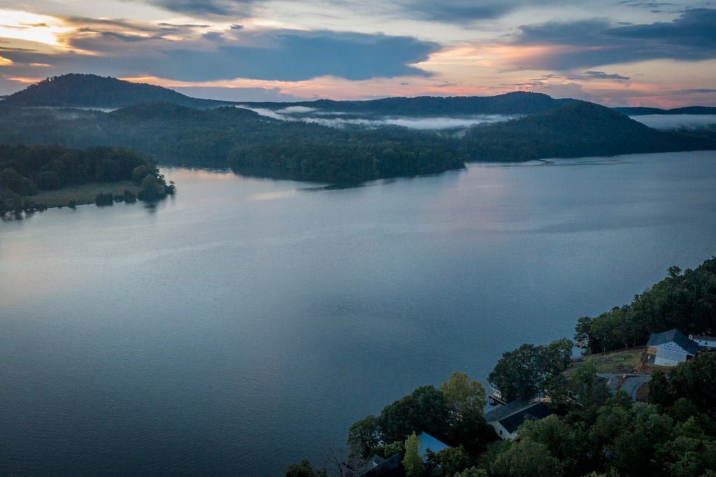 An aerial view of a lake with mountains in the background at sunset.