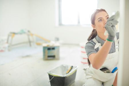 a woman is painting a wall in a room .