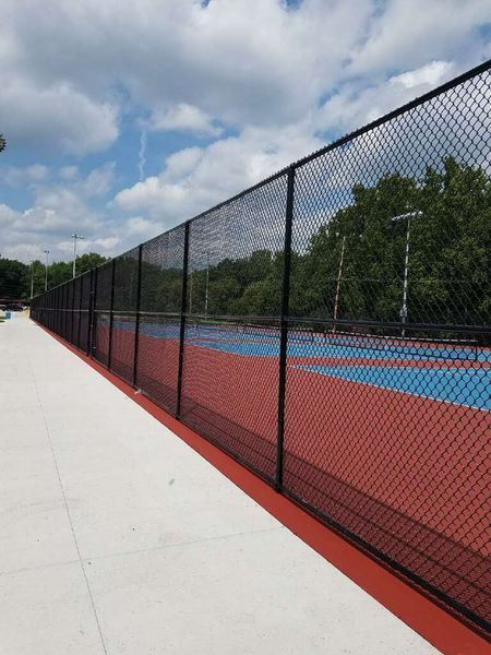 Black chain-link fence bordering a blue and red sports court