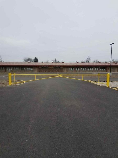 Yellow gate blocking a paved driveway