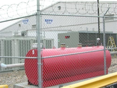 Red fuel tank behind a chain-link fence 