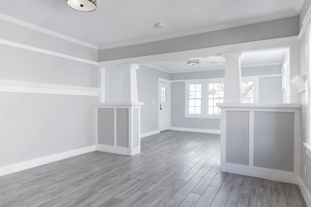 an empty living room with hardwood floors and white walls .