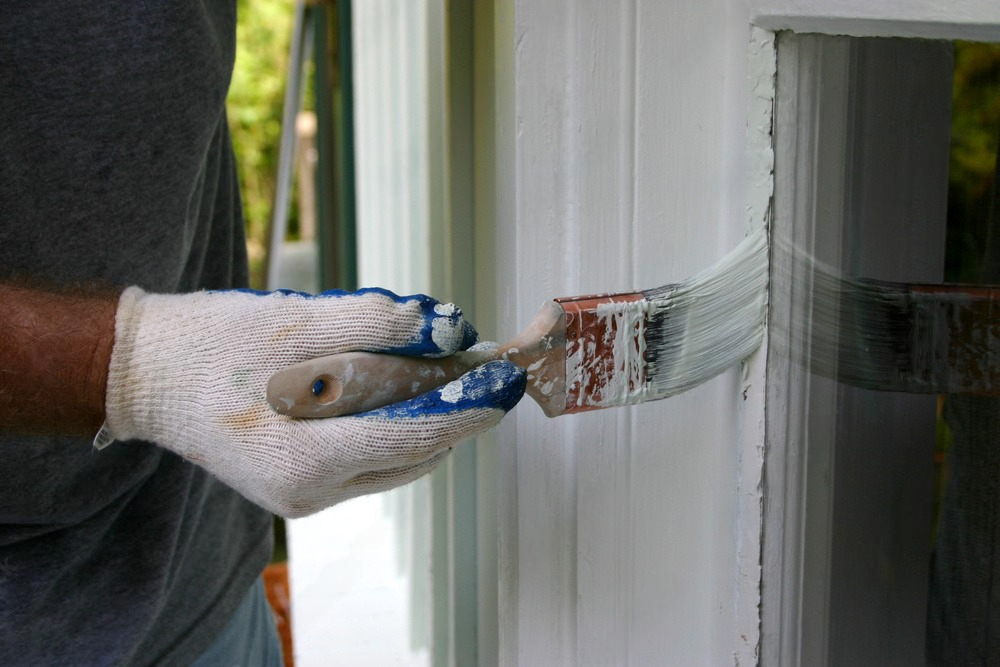 a man is painting a window with a brush .