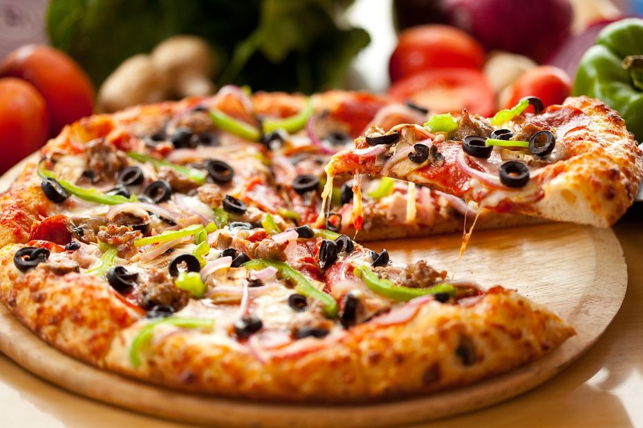 Vegetable pizza with olives, peppers, and tomatoes on a wooden board