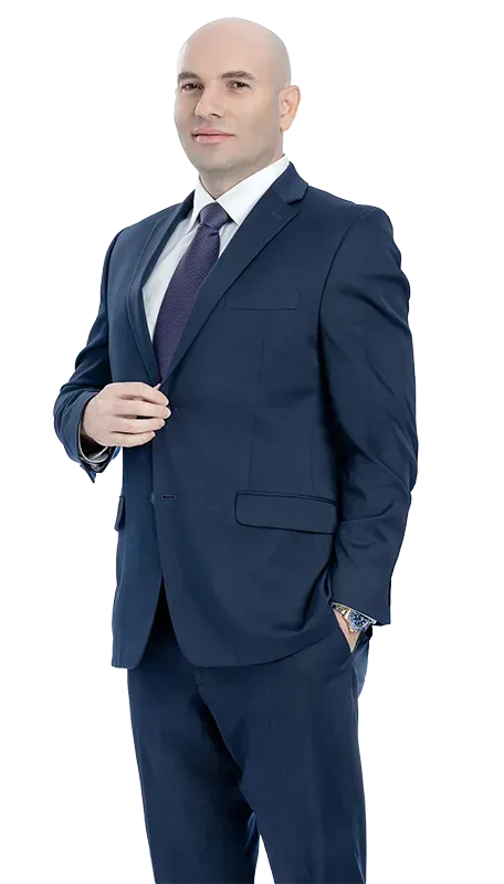 A man in a suit and tie is standing with his hands in his pockets.