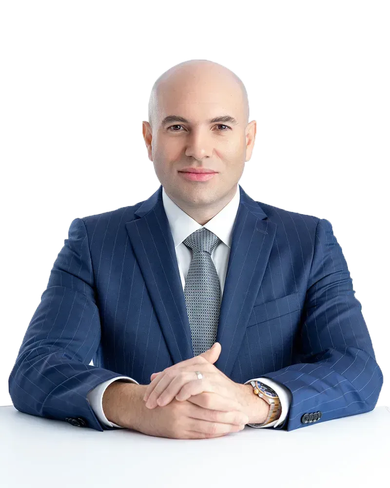 A man in a suit and tie is sitting with his hands folded