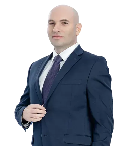 A man in a suit and tie is standing with his hands in his pockets.