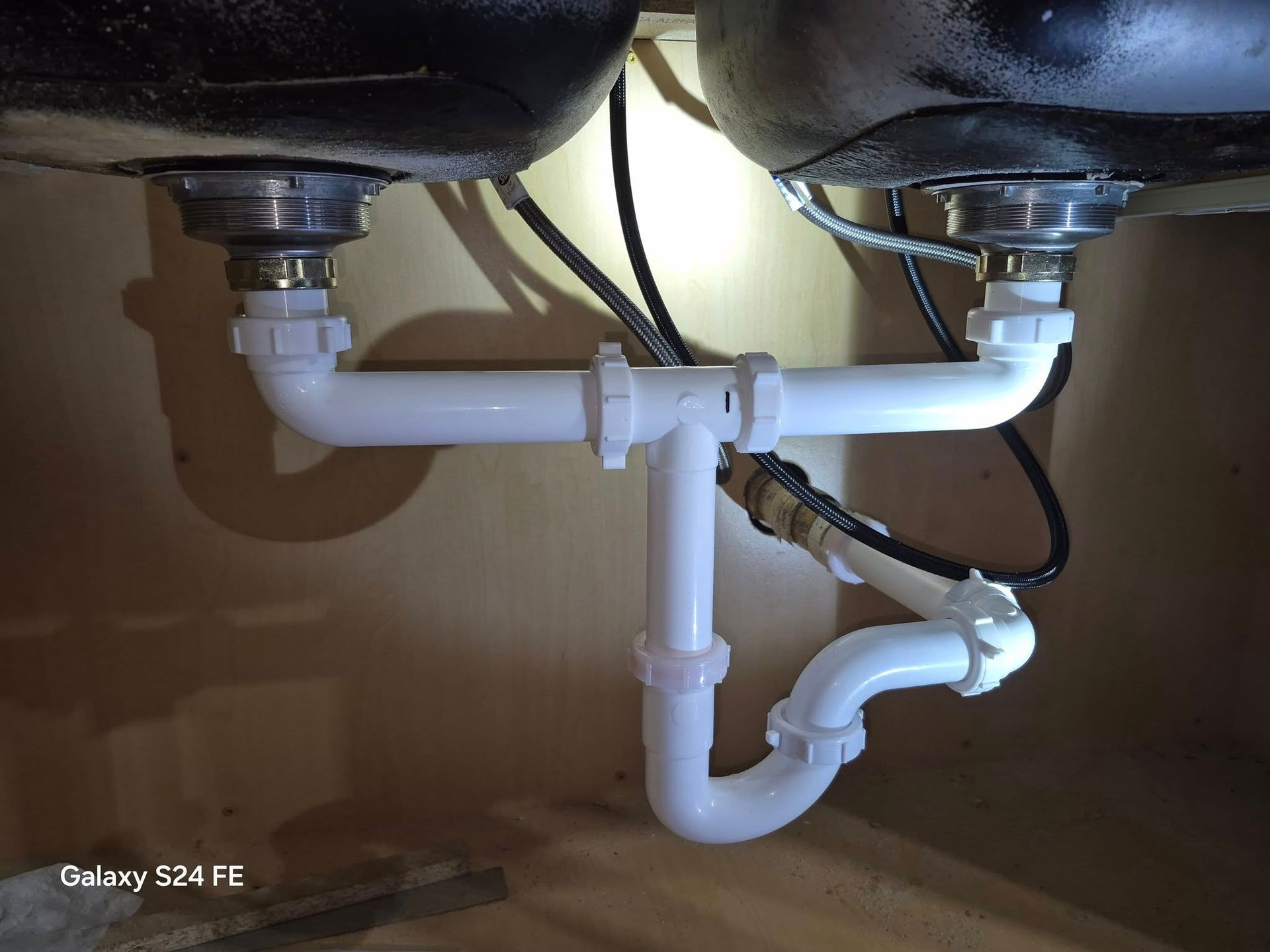 A sink with two pipes underneath it.