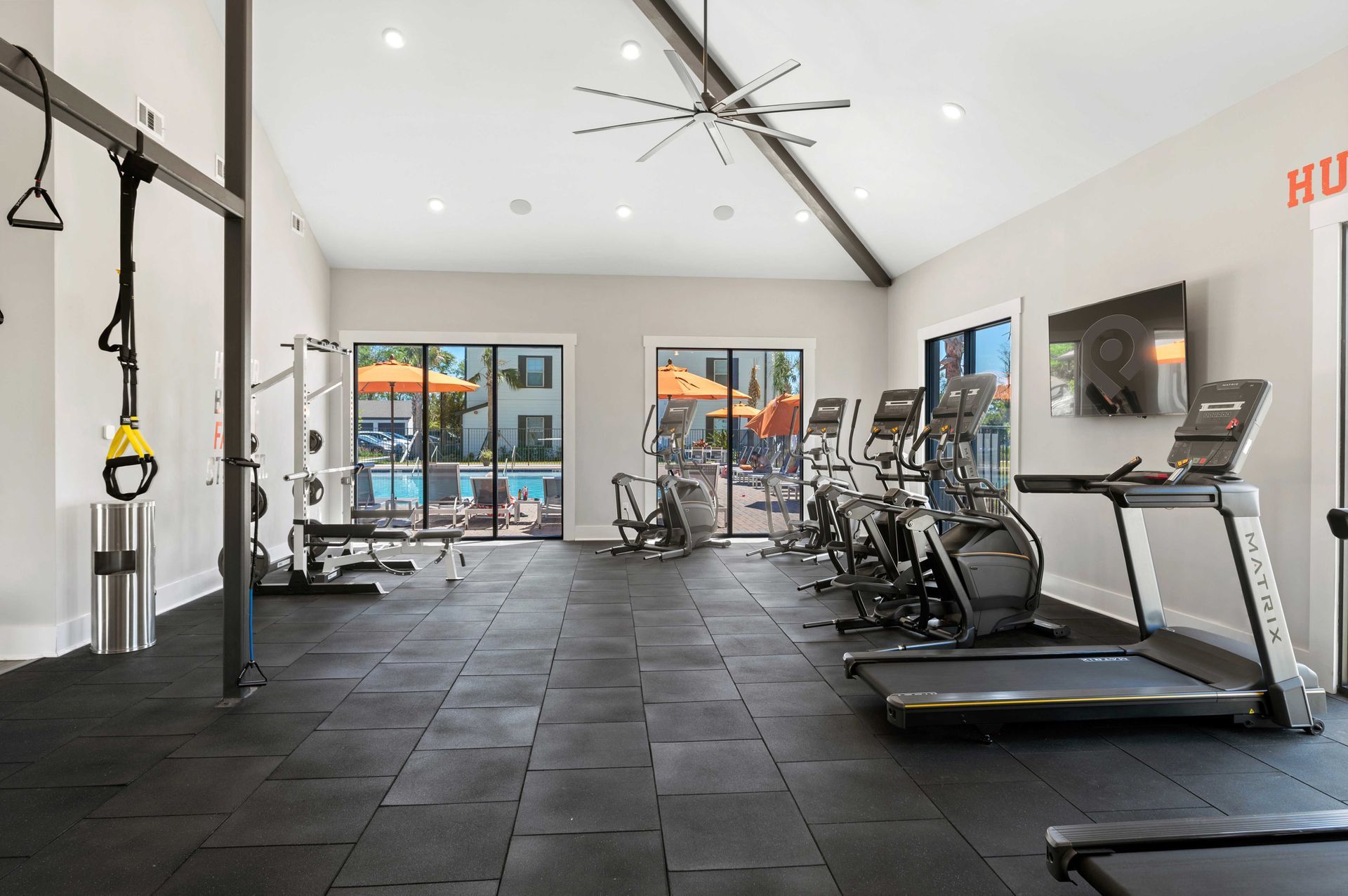 A large gym with treadmills, exercise bikes, and a ceiling fan.
