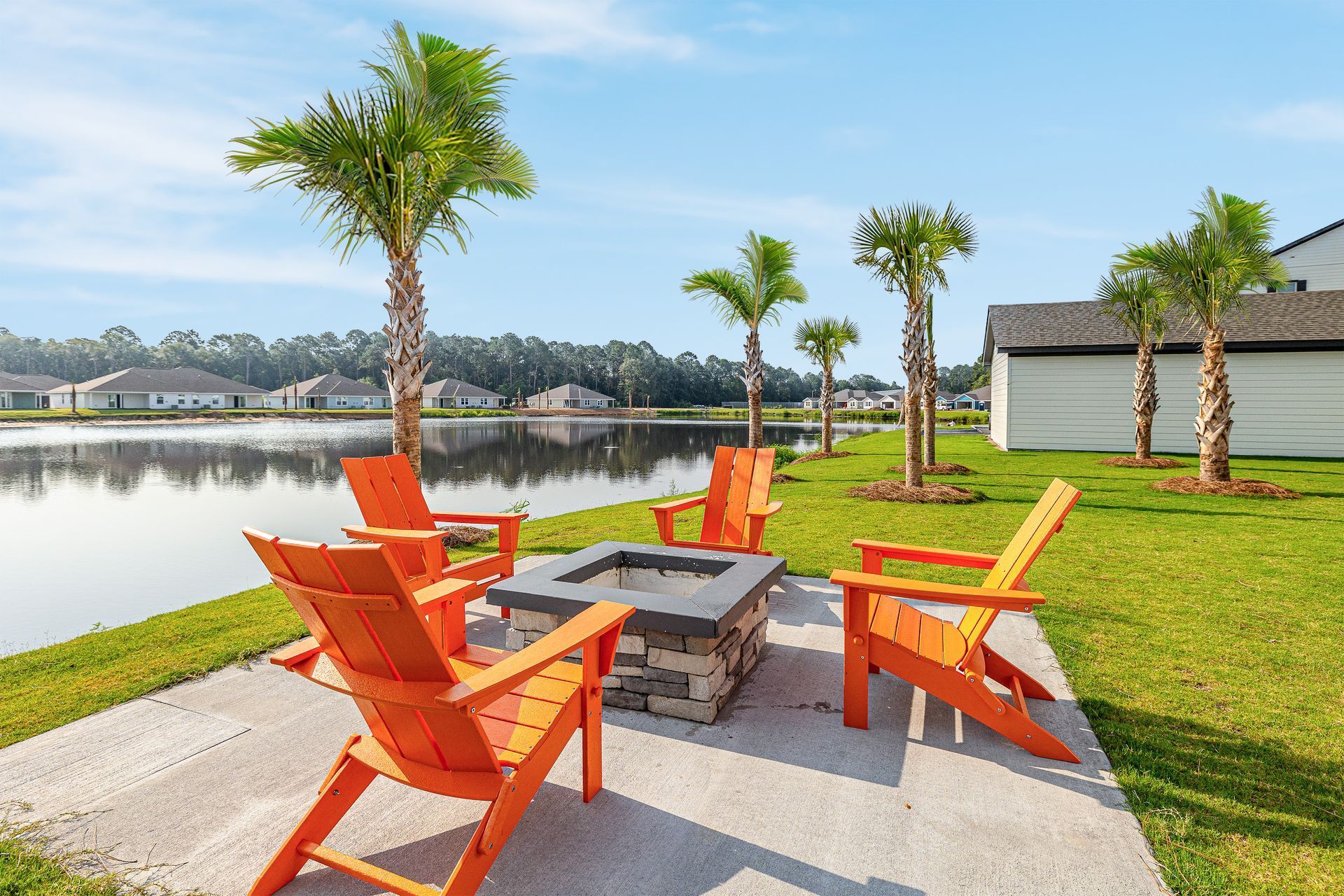 A group of orange chairs are sitting around a fire pit next to a lake at Pointe Grand Brunswick in Brunswick, GA.