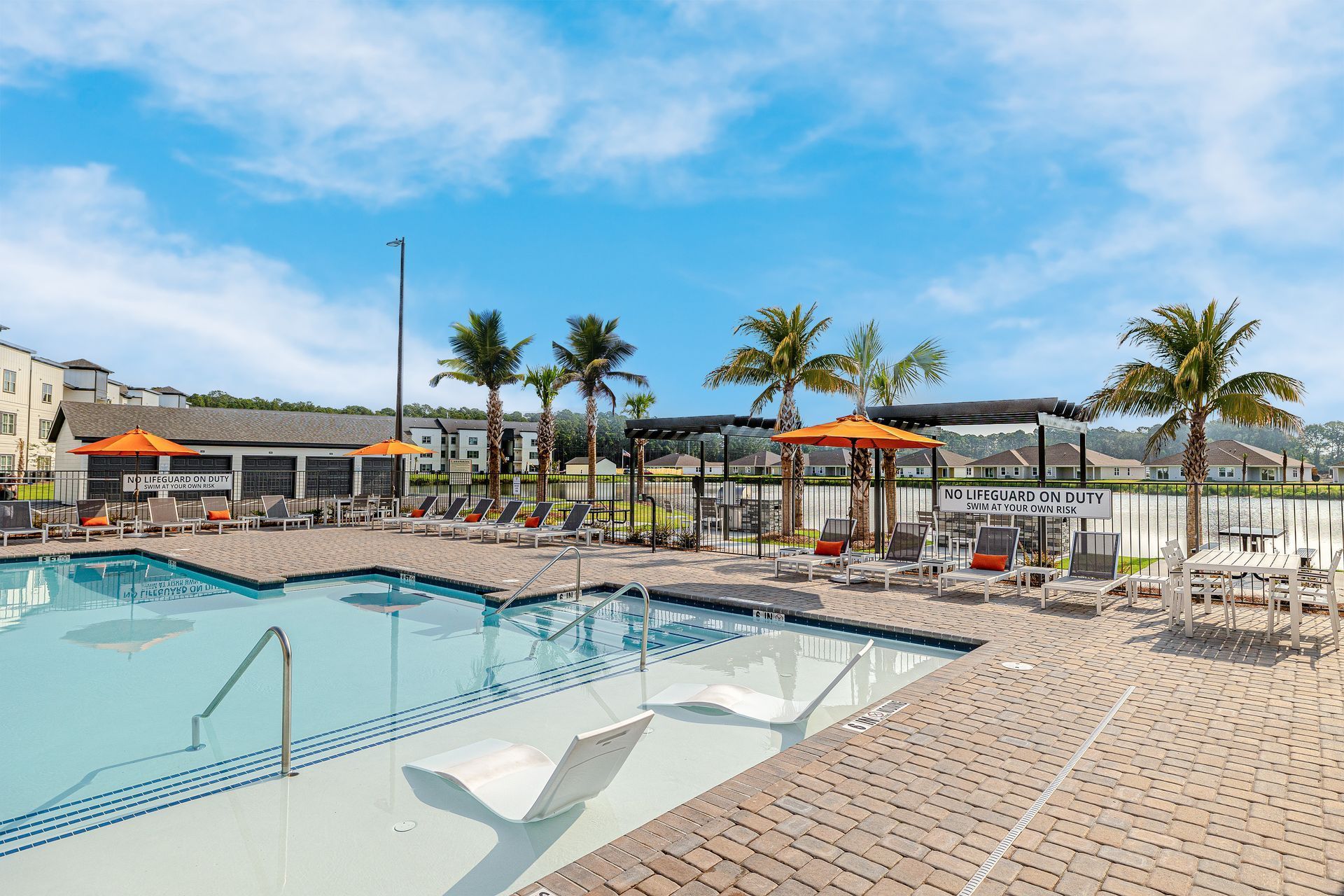 A large swimming pool surrounded by chairs and umbrellas at Pointe Grand Brunswick in Brunswick, GA.