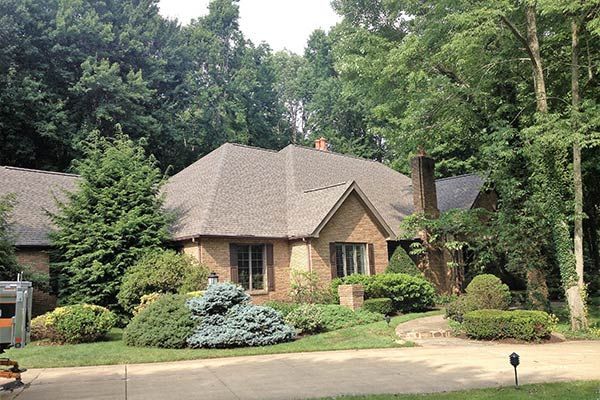 A House With A Roof That Is Surrounded By Trees — Akron, OH — D&M Roofing LLC