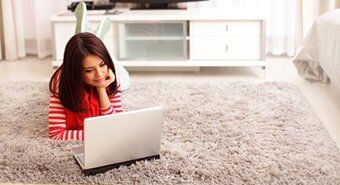 Woman laying on carpet with her laptop — Carpet & Floor Care Service in Portland, ME
