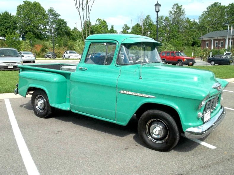Teal vintage pickup truck parked in a lot.