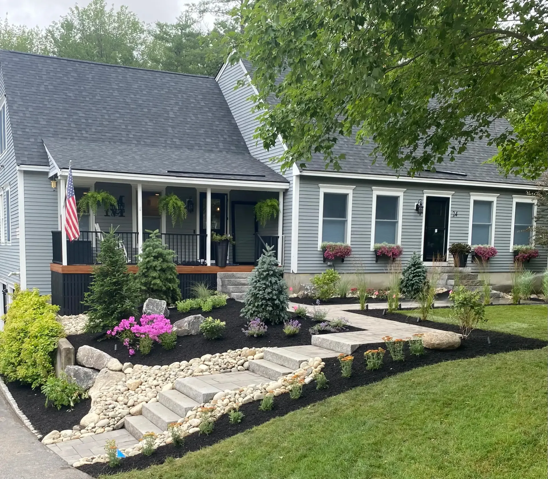 Gray house with landscaped front yard, stone steps, and flower boxes.