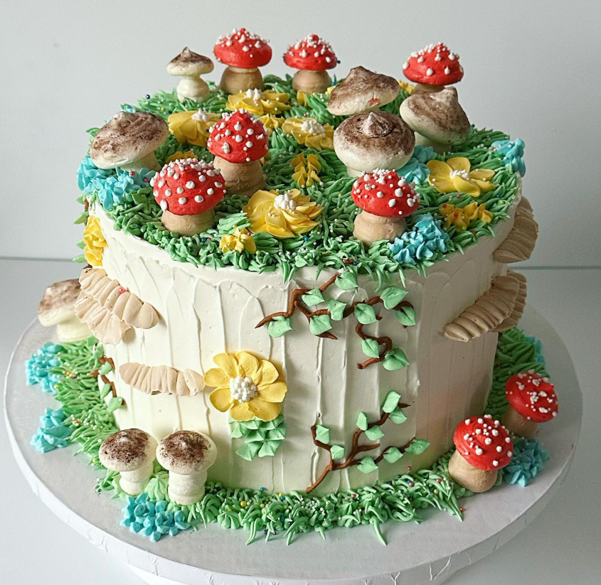 Cake decorated to resemble a woodland scene. Features frosting grass, mushrooms, and yellow flowers.