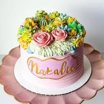 Pink frosted cake with buttercream succulents, two pink roses, and