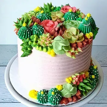 A cake decorated with buttercream succulents in shades of green, yellow, and pink.