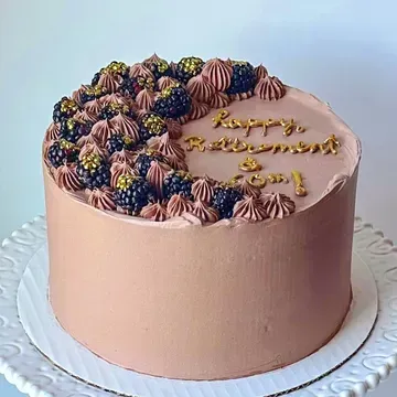 Chocolate frosted cake decorated with blackberries, gold sprinkles, and the message