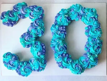 Cupcake arrangement spelling out the number 30 in shades of blue and purple frosting, decorated with sprinkles.