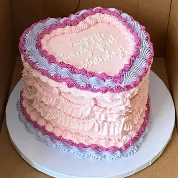 Pink heart-shaped cake with ruffled frosting and