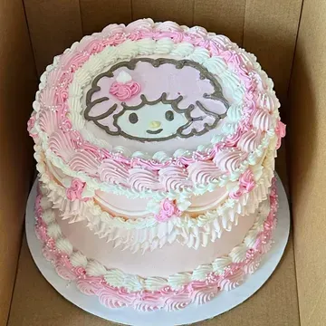 Two-tiered pink cake with white frosting, a My Melody image on top, and decorative swirls.
