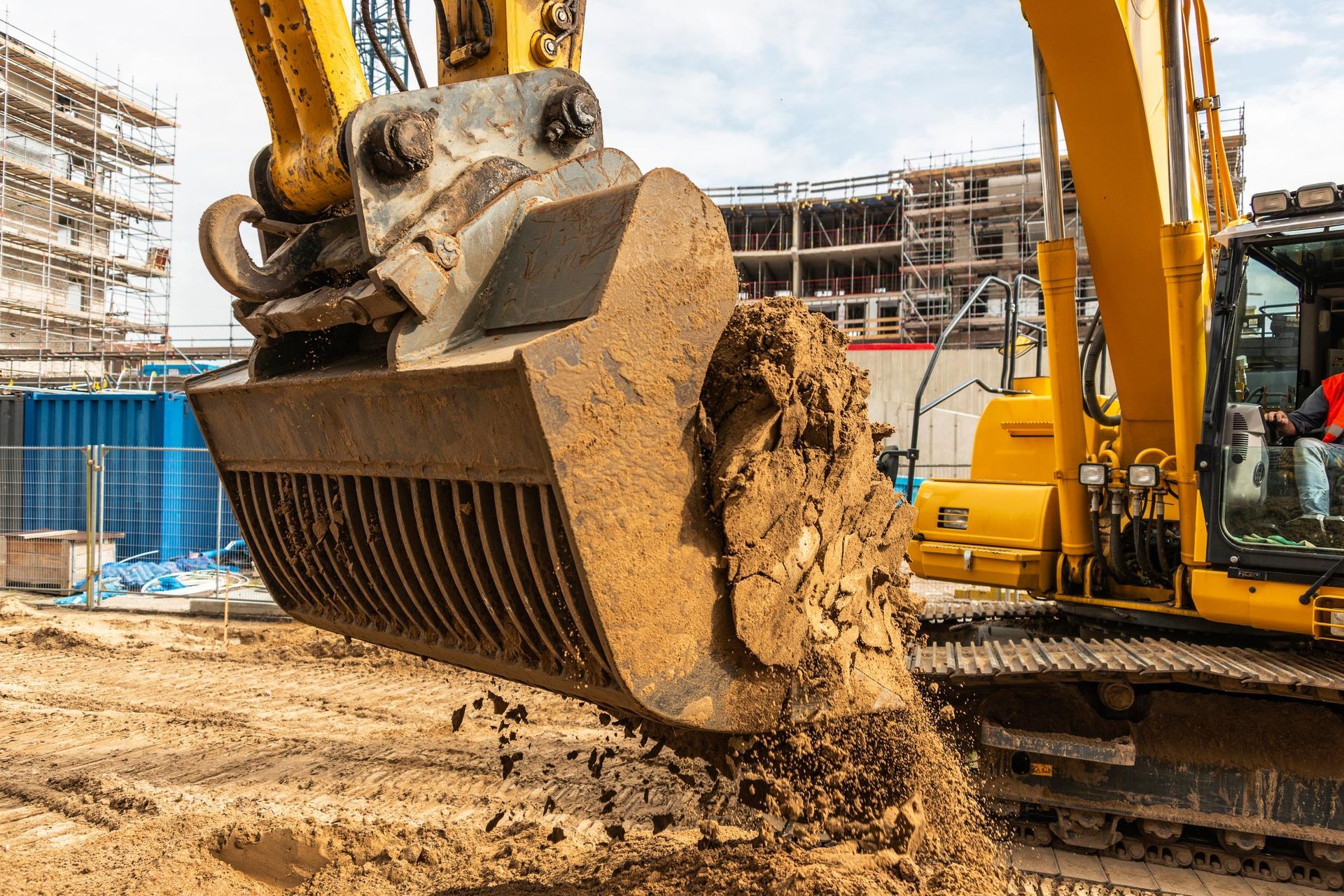 A yellow excavator is digging dirt on a construction site.