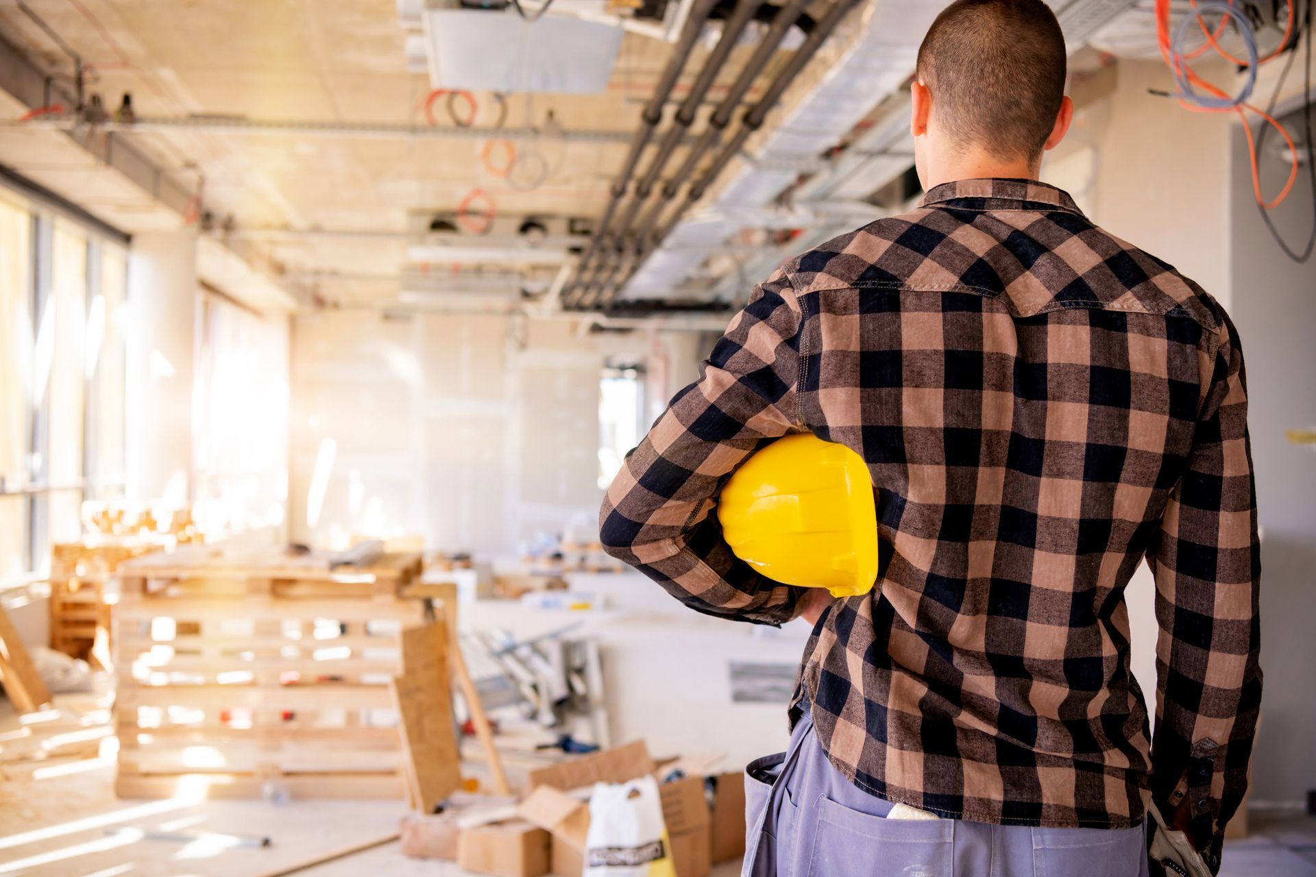A construction worker is holding a hard hat in a building under construction.