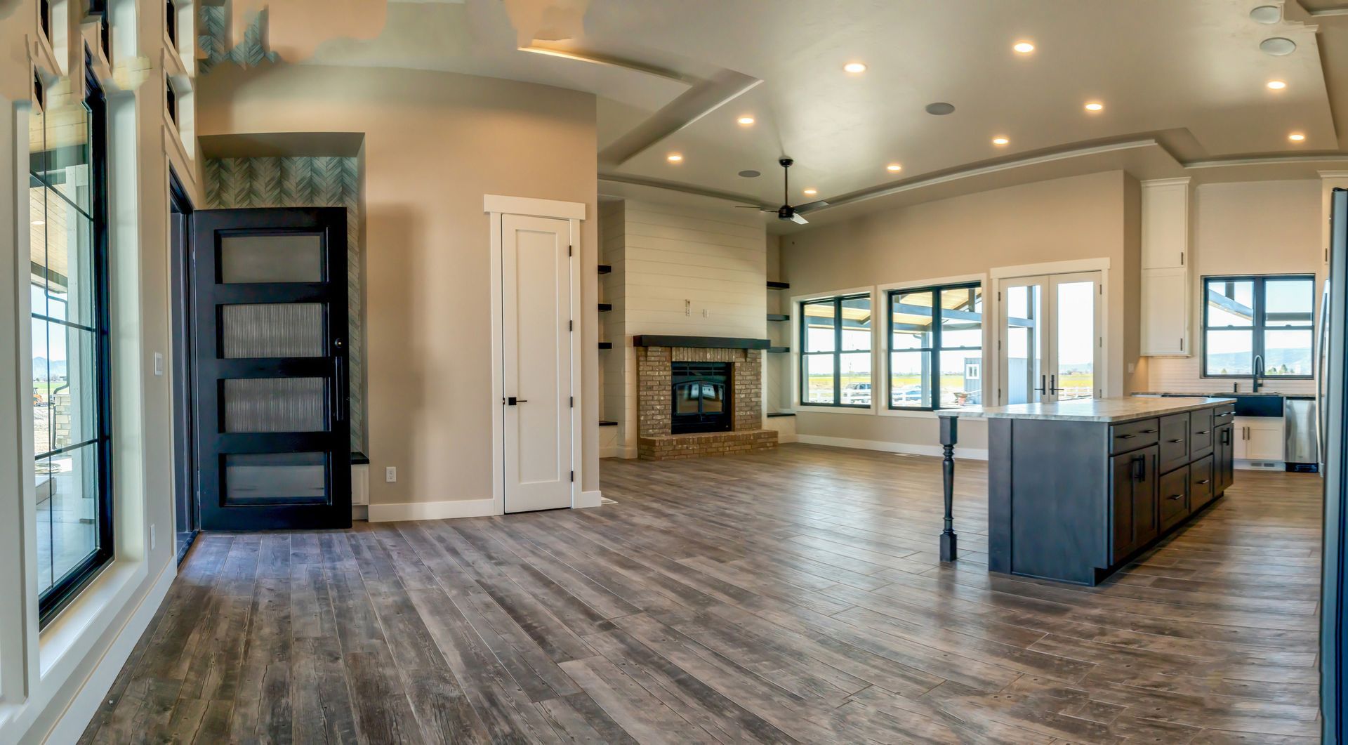 A large empty room with hardwood floors and a fireplace in a house.