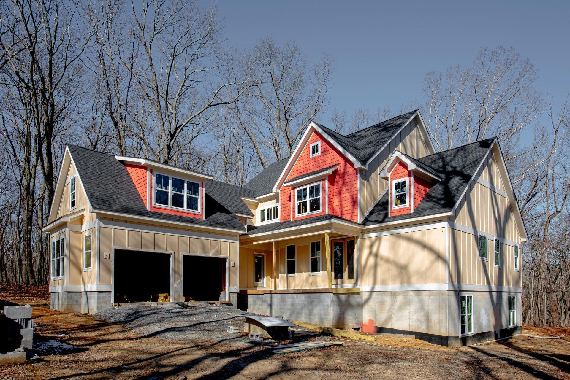 A large house with a red roof is being built in the woods.