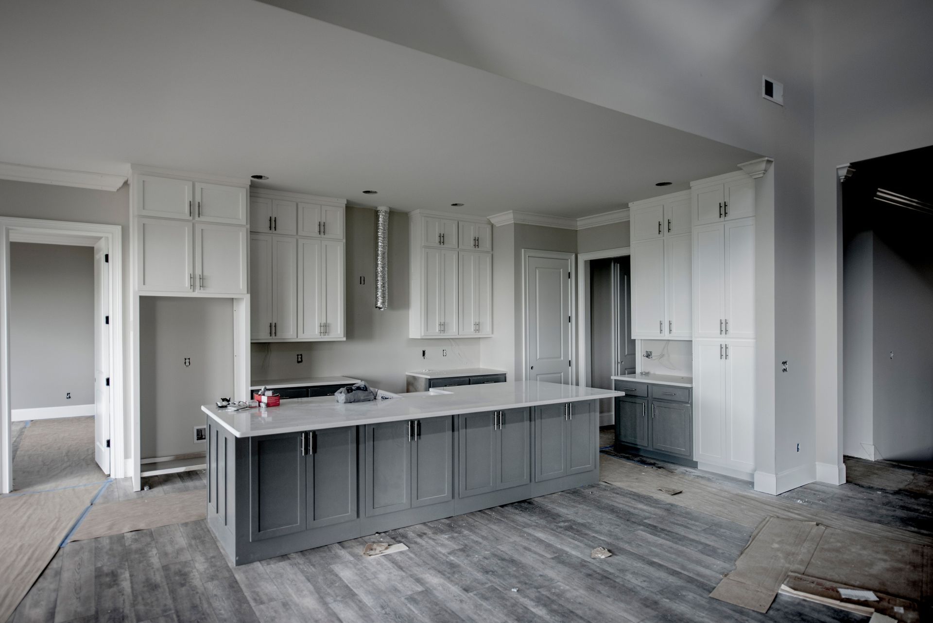 A kitchen in a house under construction with gray cabinets and a large island.