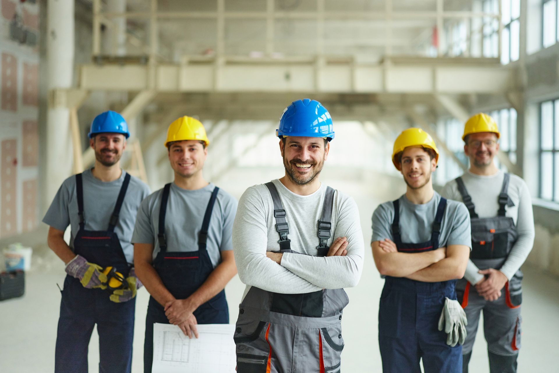 A group of construction workers are posing for a picture in a building.