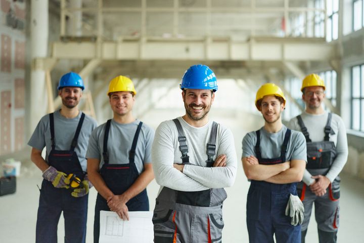 A group of construction workers are posing for a picture in a building.