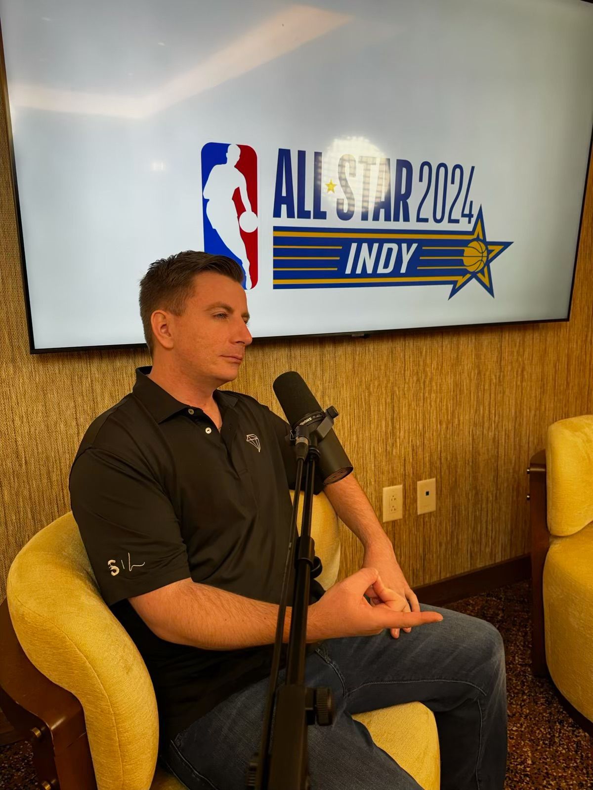 A man is sitting in front of a screen that says all star indy