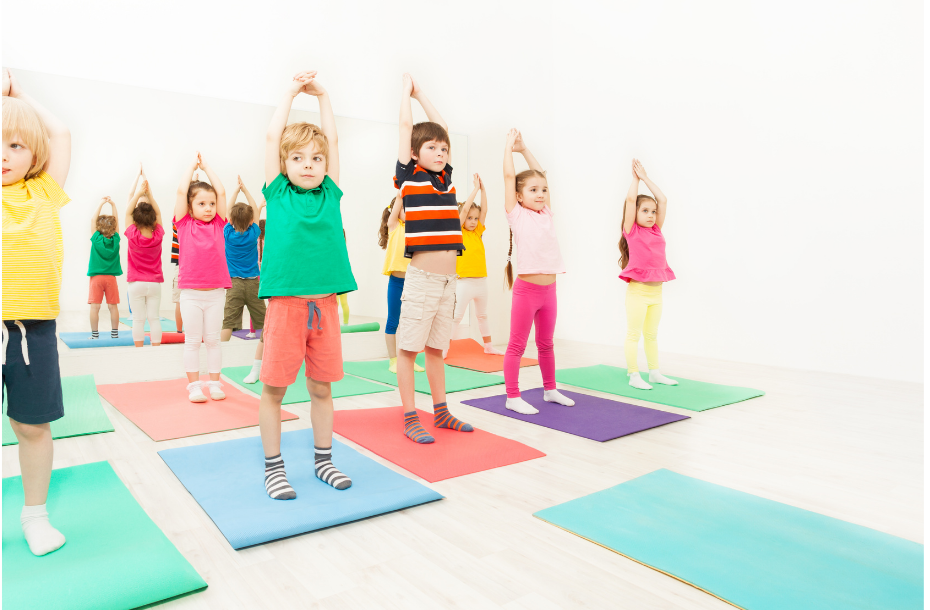 A group of children are doing yoga in a gym.