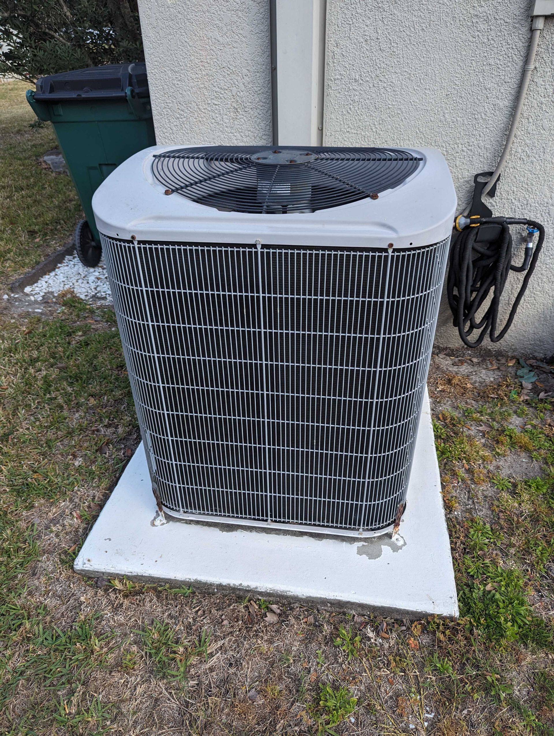 A white air conditioner is mounted on the side of a brick building.