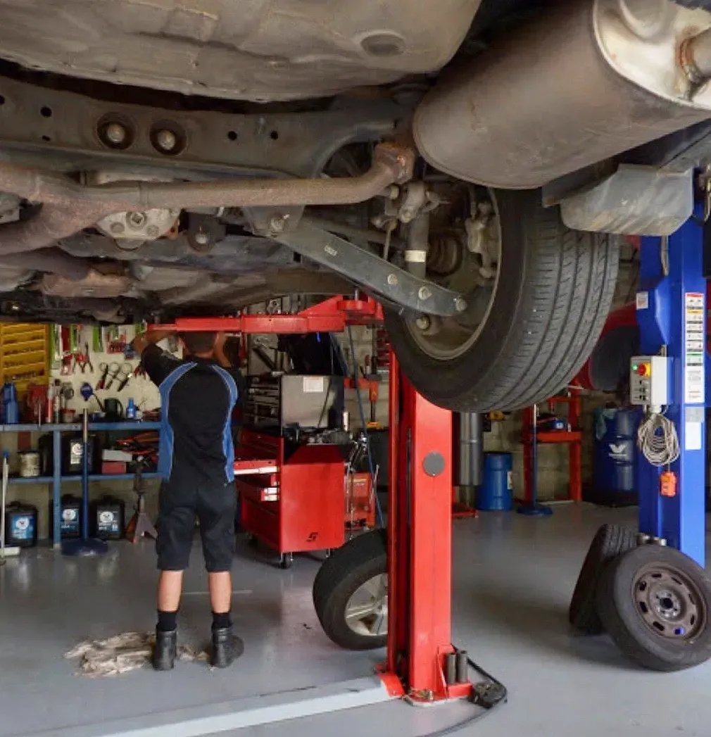 A Mechanic Working On a Car Lifted On  A Hoist — D R Automotive in Russell Vale, NSW