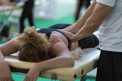 Person receiving a back massage on a massage table; masseuse's hands visible.