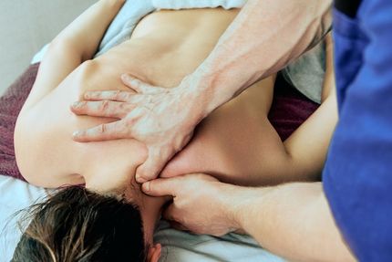 Person receiving a back massage; therapist's hands on shoulder and neck.