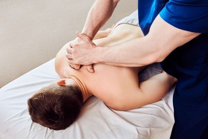 Person receiving a back massage on a massage table, hands of massage therapist visible.