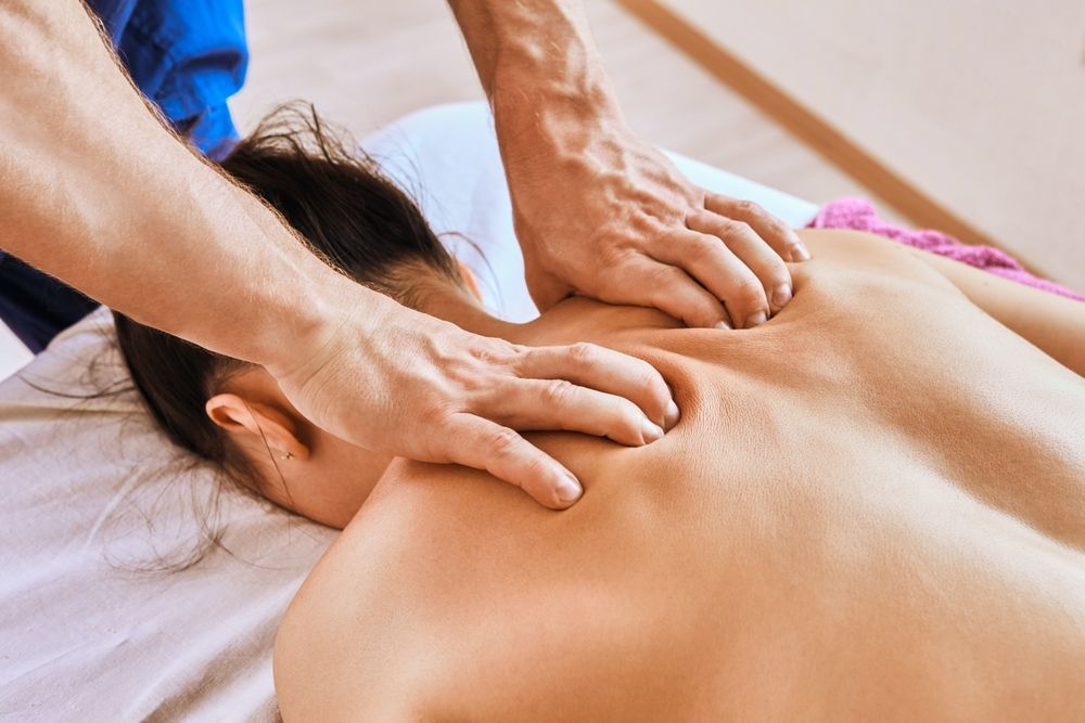 Person receiving a back massage; therapist's hands kneading the back muscles.