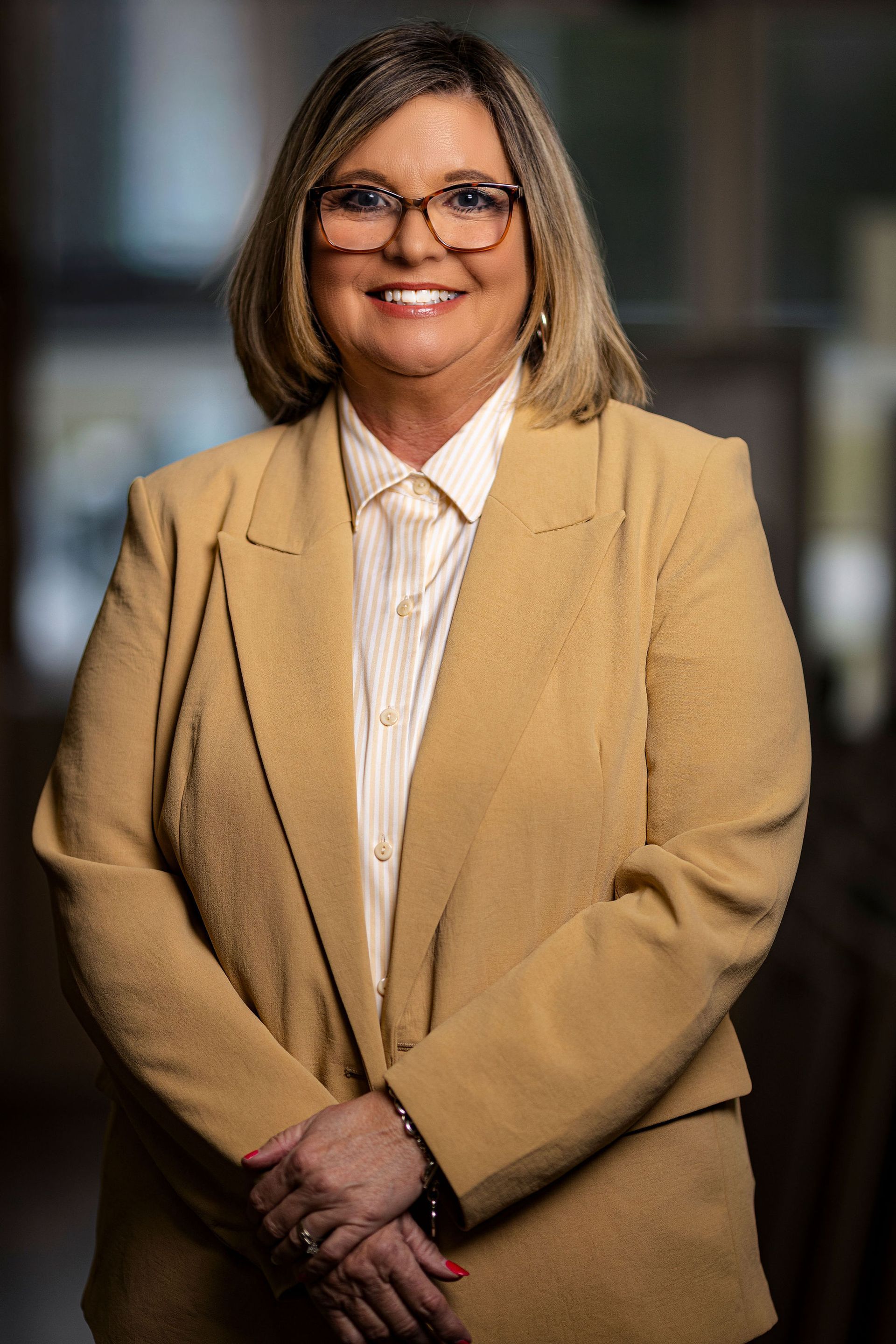 A woman wearing glasses and a black shirt is smiling for the camera.