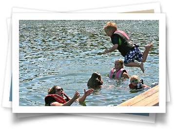 A group of children are jumping into a lake.