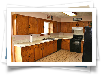 A kitchen with wooden cabinets and a black refrigerator