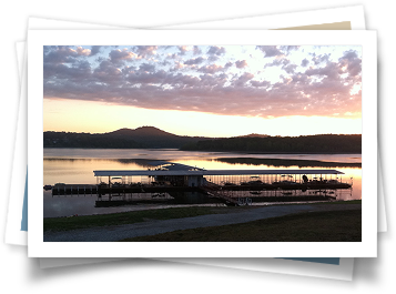 A picture of a dock on a lake at sunset